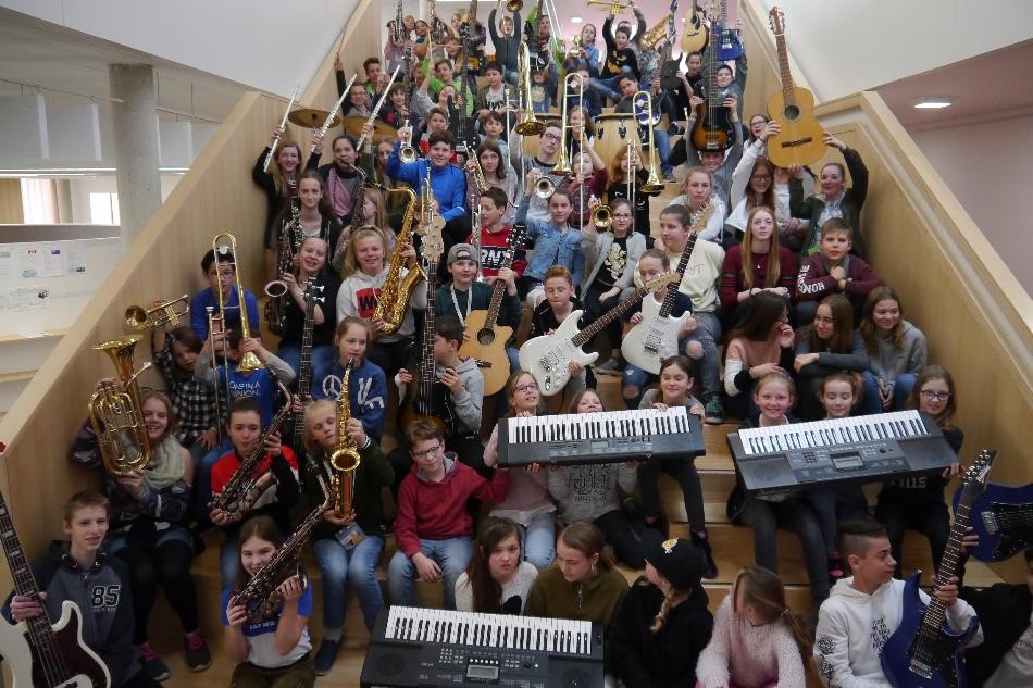 Schüler und Intrumente Eine große Gruppe Schüler sitzt mit Instrumenten auf der großen Schultreppe